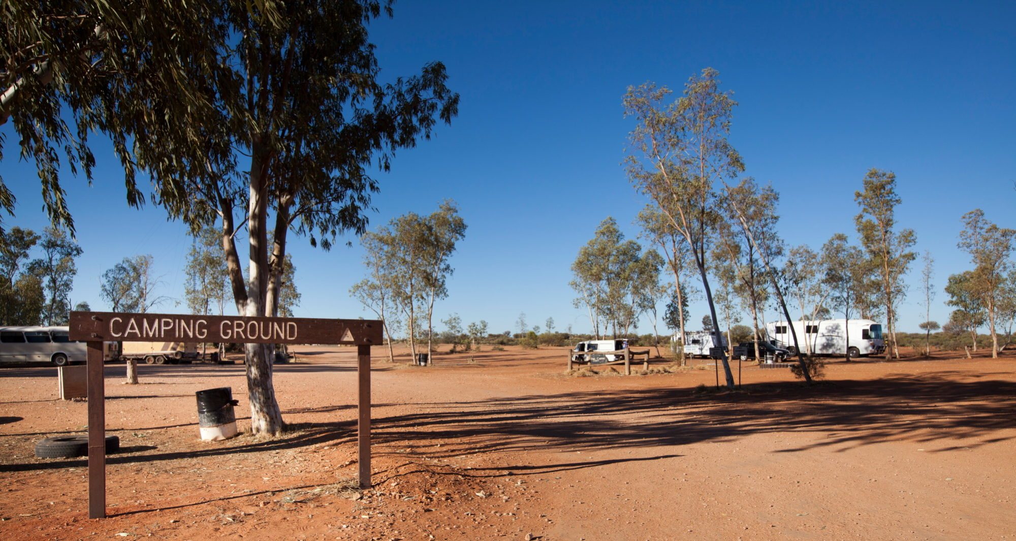 The Curtin Springs camping ground sign beneath desert oaks and blue sky