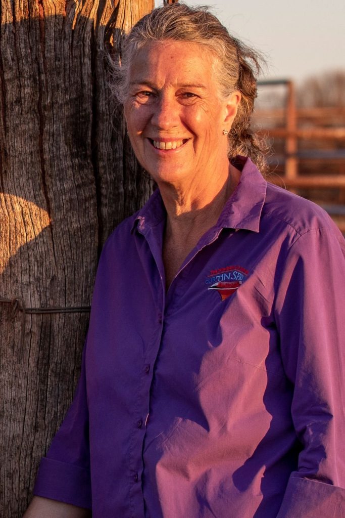 Lyndee Severin in a purple Curtin Springs shirt beside a tree.