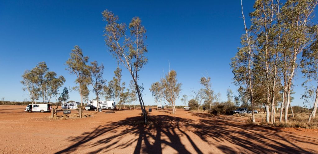 Caravans and campers among desert oaks on the red-dirt campground