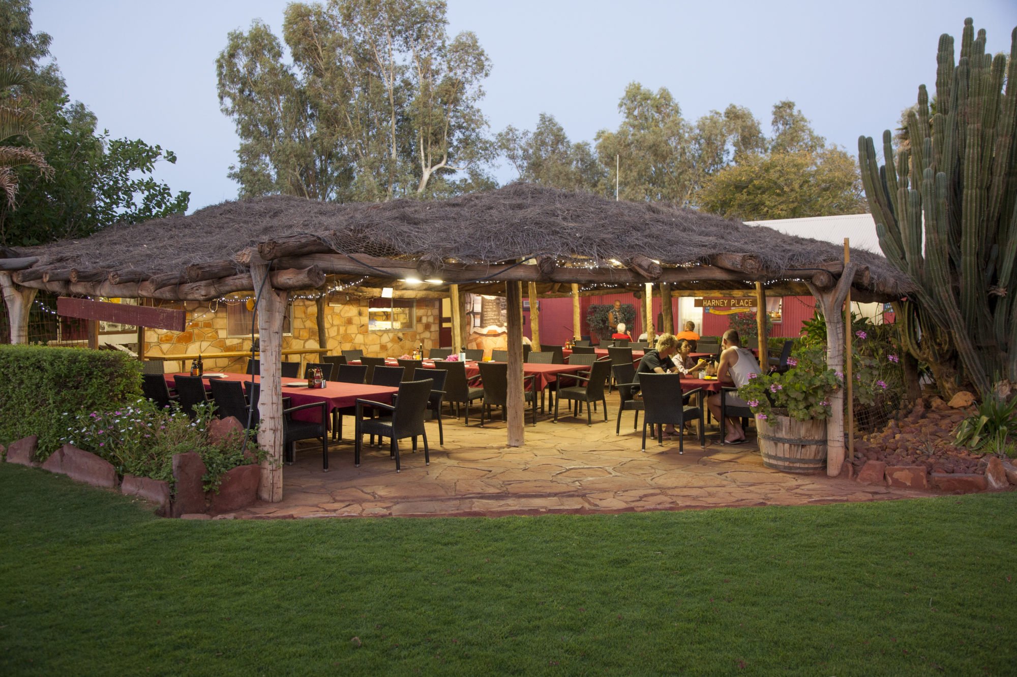 The historic Bough Shed lit up at dusk with tables set beneath its leafy roof