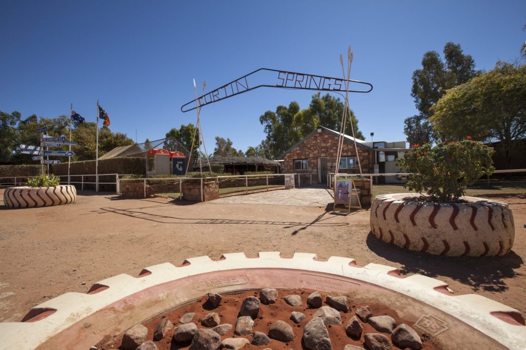 The Curtin Springs Wayside Inn entrance arch and gardens beyond a stone-edged garden bed