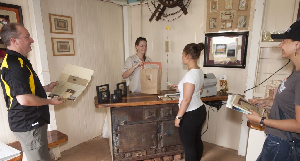 A guide showing visitors framed Curtin Springs Paper artworks in The Gallery