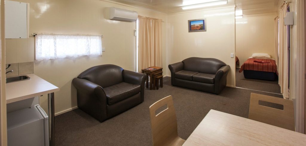 Family room living area with two leather lounges, a table and the bedroom beyond